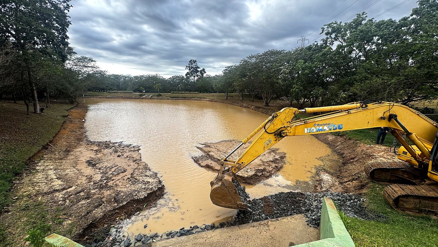 Escavadeira aplicando enrocamento na saída de drenagem com o lago em enchimento