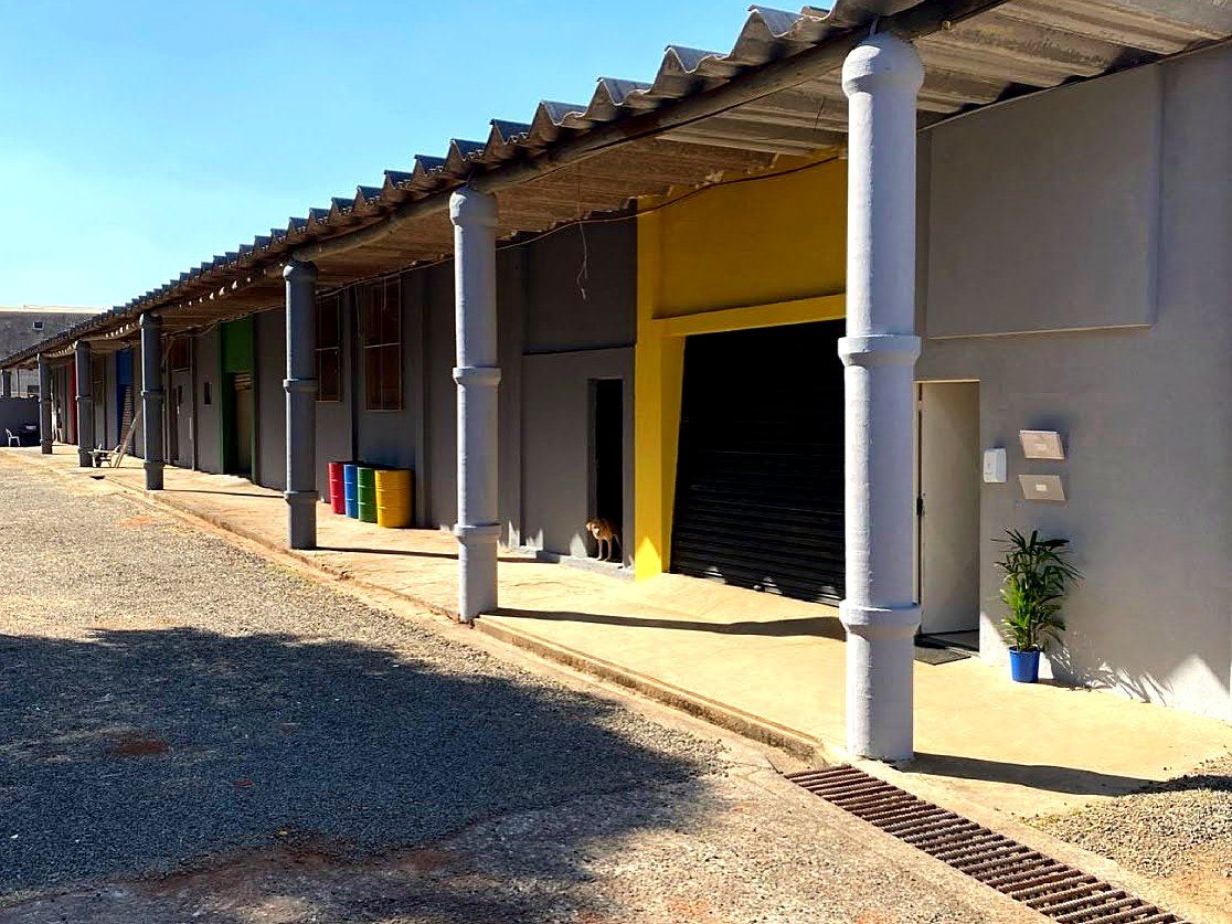 Galpões da base com baias coloridas e tambores de coleta seletiva